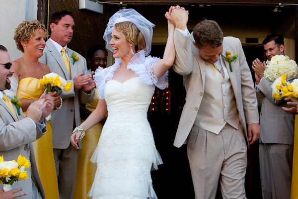 couple laughing as they exit the ceremony - groomsmen in light tan suits with yellow ties and boutonnieres, bridesmaids in yellow strapless dresses - photo by Seattle based wedding photographers La Vie Photography